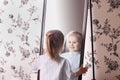 Little blond girl in striped shirt looking at his reflectio