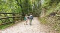 Little blond girl with a tourist backpack points a finger at a mountain lake. Children in camping gear go on a family weekend Royalty Free Stock Photo