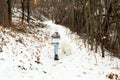 Little blond girl in winter clothes walking with her samoyed dog in snowy forest path Royalty Free Stock Photo