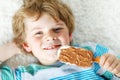 Little blond kid boy with curly hairs eating ice cream popsicle with chocolate at home or in kindergarten. Happy child Royalty Free Stock Photo