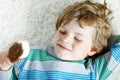 Little blond kid boy with curly hairs eating ice cream popsicle with chocolate at home Royalty Free Stock Photo