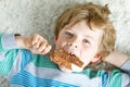 Little blond kid boy with curly hairs eating ice cream popsicle with chocolate at home Royalty Free Stock Photo