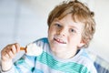 Little blond kid boy with curly hairs eating ice cream popsicle with chocolate at home Royalty Free Stock Photo