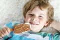 Little blond kid boy with curly hairs eating ice cream popsicle with chocolate at home Royalty Free Stock Photo