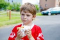 Little blond kid boy eating hot dog after playing soccer. Royalty Free Stock Photo