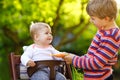 Little blond kid boy giving a carrot to baby sister. Happy siblings eating healthy snack. Baby girl sitting in pram or Royalty Free Stock Photo