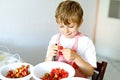 Little blond kid boy helping and making strawberry jam in summer Royalty Free Stock Photo