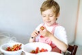 Little blond kid boy helping and making strawberry jam in summer Royalty Free Stock Photo