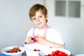 Little blond kid boy helping and making strawberry jam in summer Royalty Free Stock Photo