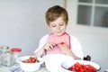 Little blond kid boy helping and making strawberry jam in summer Royalty Free Stock Photo