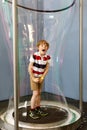 Little blond kid boy playing with huge soap bubbles construction indoors. Happy healthy smiling child having fun with Royalty Free Stock Photo