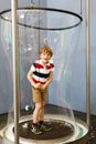 Little blond kid boy playing with huge soap bubbles construction indoors. Happy healthy smiling child having fun with Royalty Free Stock Photo