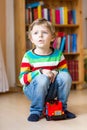 Little blond kid boy playing with wooden toy bus, indoors Royalty Free Stock Photo