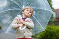 Little blond kid boy walking with big umbrella outdoors Royalty Free Stock Photo