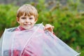 Little blond kid boy walking with big umbrella outdoors on rainy day. Portrait of cute preschool child having fun wear Royalty Free Stock Photo