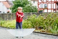 Little blond kid boy walking with big umbrella outdoors on rainy day. Portrait of cute preschool child having fun wear Royalty Free Stock Photo