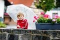 Little blond kid boy walking with big umbrella outdoors on rainy day. Portrait of cute preschool child having fun wear Royalty Free Stock Photo