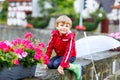 Little blond kid boy walking with big umbrella outdoors on rainy day. Portrait of cute preschool child having fun wear Royalty Free Stock Photo