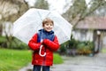 Little blond kid boy on way to school walking during sleet, rain and snow with an umbrella on cold day Royalty Free Stock Photo