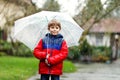 Little blond kid boy on way to school walking during sleet, rain and snow with an umbrella on cold day Royalty Free Stock Photo