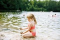 Little blond preschool girl having fun with playing with sand on lake on summer day, outdoors. Happy child learning Royalty Free Stock Photo