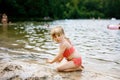 Little blond preschool girl having fun with playing with sand on lake on summer day, outdoors. Happy child learning Royalty Free Stock Photo