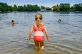 Little blond preschool girl having fun with splashing in a lake on summer day, outdoors. Happy child learning swimming Royalty Free Stock Photo