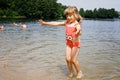 Little blond preschool girl having fun with splashing in a lake on summer day, outdoors. Happy child learning swimming Royalty Free Stock Photo