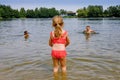 Little blond preschool girl having fun with splashing in a lake on summer day, outdoors. Happy child learning swimming Royalty Free Stock Photo