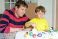 Little blond preschool kid boy and father coloring eggs for Easter holiday Royalty Free Stock Photo