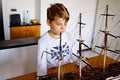 Little blond school kid boy playing with sailing ship model indoors. Excited child with yacht having fun after school at Royalty Free Stock Photo