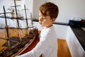 Little blond school kid boy playing with sailing ship model indoors. Excited child with yacht having fun after school at Royalty Free Stock Photo