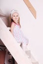 Little blond smiling girl in dress sitting on wooden stairs Royalty Free Stock Photo