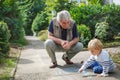 Little blond toddler boy and happy grandfather painting with chalk outdoors Royalty Free Stock Photo