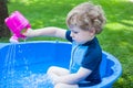 Little blond toddler boy playing with water in summer Royalty Free Stock Photo