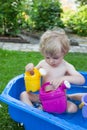 Little blond toddler boy playing with water in summer Royalty Free Stock Photo