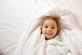 Little blond toddler child, boy, smiling at the camera, wrapped in towels after bath Royalty Free Stock Photo