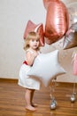 Little blonde baby girl two years old with big pink and white balloons on her birthday party Royalty Free Stock Photo