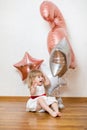 Little blonde baby girl two years old with big pink and white balloons on her birthday party Royalty Free Stock Photo