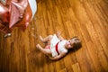 Little blonde baby girl two years old with big pink and white balloons lying on the wooden floor on her birthday party Royalty Free Stock Photo