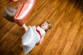 Little blonde baby girl two years old with big pink and white balloons lying on the wooden floor on her birthday party Royalty Free Stock Photo