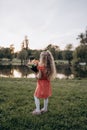 A little blonde with a bouquet in her hand looks into the distance with her back to the camera