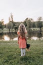 A little blonde with a bouquet in her hand looks into the distance with her back to the camera