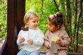 A little blonde boy and an African-American girl in a park on a bench eating a bar of white and dark chocolate Royalty Free Stock Photo