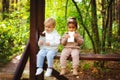 A little blonde boy and an African-American girl in a park on a bench eating a bar of white and dark chocolate Royalty Free Stock Photo