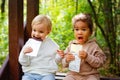 A little blonde boy and an African-American girl in a park on a bench eating a bar of white and dark chocolate Royalty Free Stock Photo