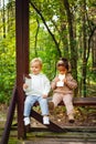 A little blonde boy and an African-American girl in a park on a bench eating a bar of white and dark chocolate Royalty Free Stock Photo