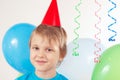 Little blonde boy in festive cap with holiday balls and streamer Royalty Free Stock Photo
