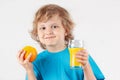 Little blonde boy with a glass of fresh juice and orange Royalty Free Stock Photo