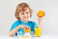 Little blonde boy makes juice from an orange Royalty Free Stock Photo